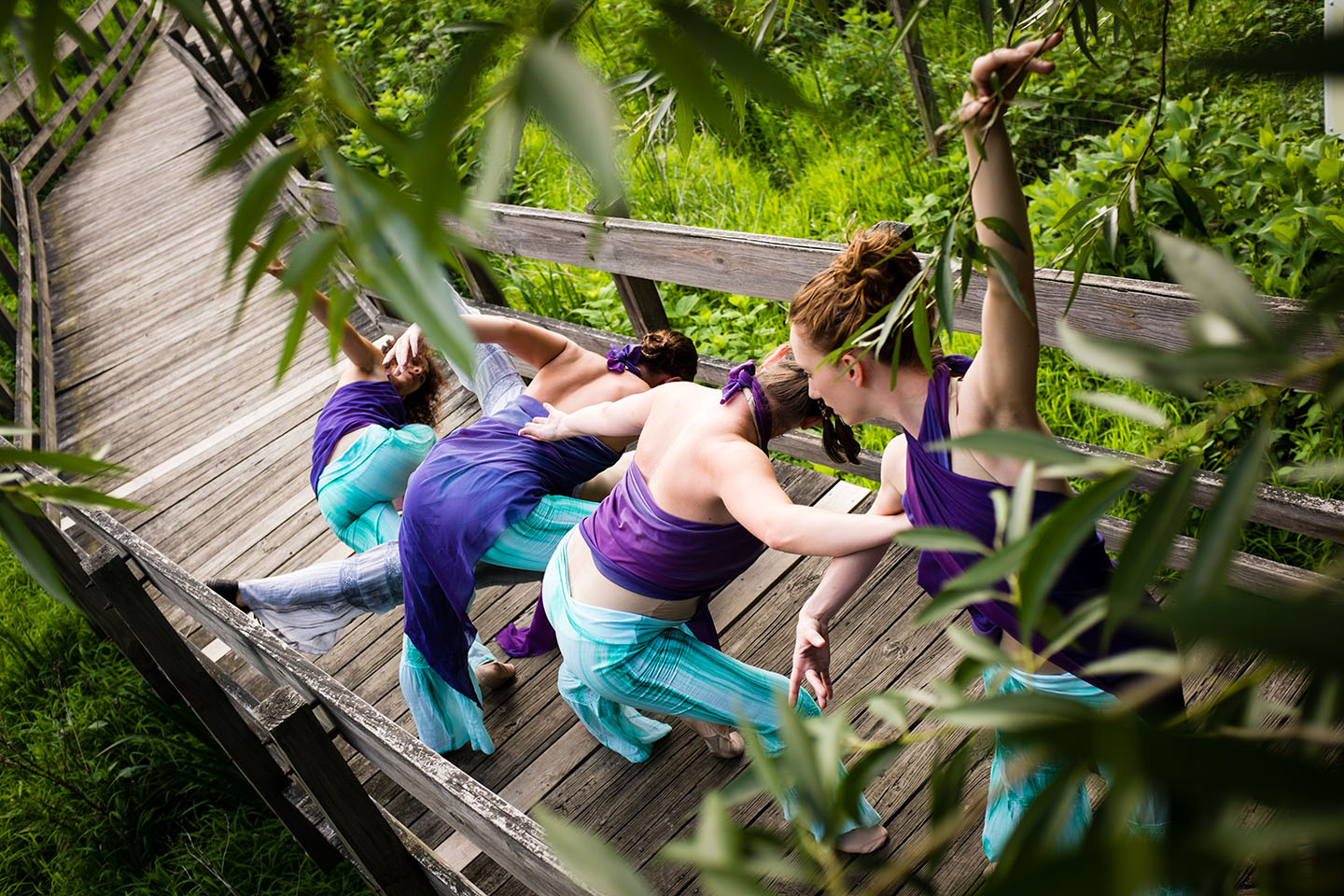 Image of 4 MorrisonDancers dancing down a wooden stairway outdoors in purple costumes