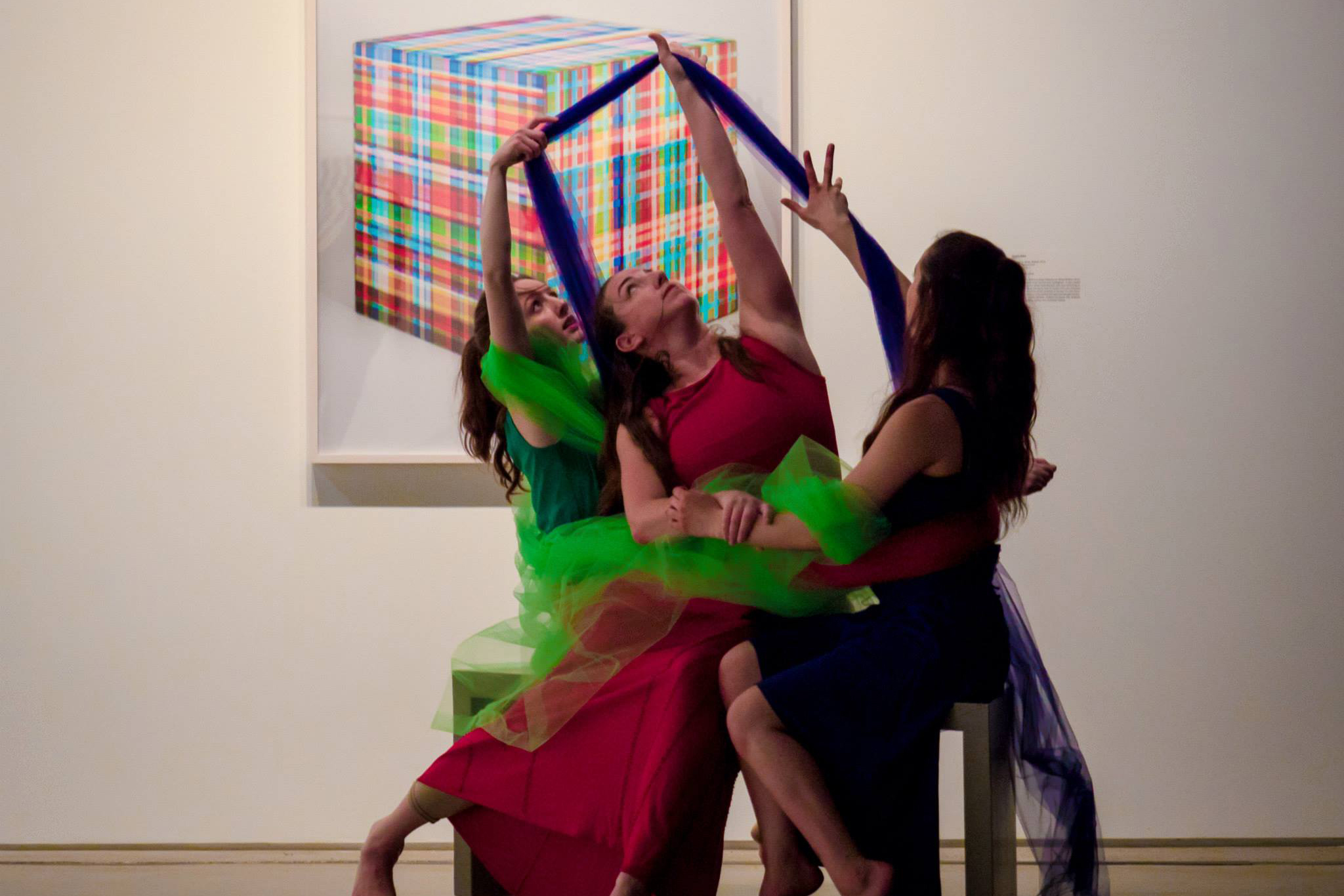 Image of 3 MorrisonDancers reaching towards the ceiling wearing red, green, and blue in their RGB performance at the Cleveland Museum of Contemporary Art